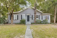 Exterior of the 1 story Willow House. There is a sidewalk leading up to the front steps, and the house has grey sidings, blue door, and green space out front.