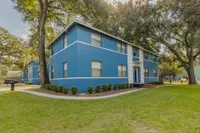 Exterior of the two story Midtown Manor building. The building is blue with white stripes, and there is a sidewalk that wraps around the building.