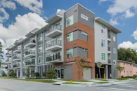 Exterior of the Edge Building. There are balconies, exposed brick walls, grey siding, and a road that leads to the parking garage.