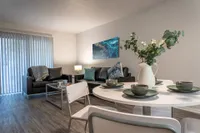 Living room with wood style floors, circular white dining set, couches, coffee table, and glass doors that lead to the back porch area.
