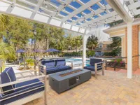 Patio seating under a pergola next to the community pool. There is a fire pit in the center of the patio set.