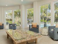 Large coffee table with wood, stones, and glass on top. There are large windows in the background facing the community pool.