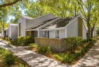 Apartment exterior with brick half wall. Shaded sidewalk along exterior.