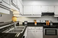 Kitchen with black granite countertop, white classic cabinets, and stainless steel oven