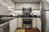 Kitchen with black granite countertop, white classic cabinets, and stainless steel oven and fridge
