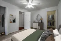 Bedroom with low queen bed and open closet. Clothes are hanging in the closet.