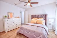 Carpeted bedroom with white walls, large windows, and white bedding.