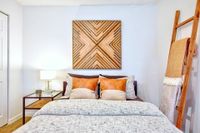 Carpeted bedroom with white walls, large windows, and white bedding.
