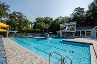 Large community pool with lounge chairs, clubhouse and leasing office in the background.