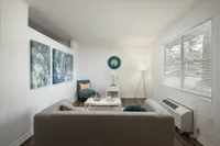 Living room with gray couch, air conditioning and wall art