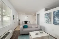 Living room with gray couch, air conditioning and wall art