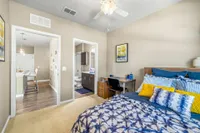 Another bedroom with blue and white bedspread.  Desk and chair on the right.  Large window with open horizontal blinds.
