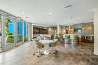 Community clubhouse with modern couch loaded with pillows.  Leasing offices behind glass walls in background.