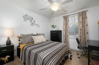 Bedroom with ceiling fan, window, furniture.