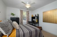 Bedroom with ceiling fan, window, furniture.