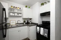 Kitchen with white cabinets, black and grey countertops, and white appliances.