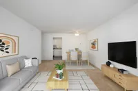 Carpeted living area with modern furniture, television, and wall art.