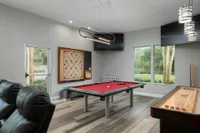 Community game and movie room with pool table, shuffleboard, leather recliners and large TV.