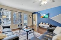 Living area with hardwood floors, white and blue accent wall, and a large window.