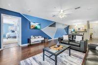 Living area with hardwood floors, white and blue accent wall, and a large window.