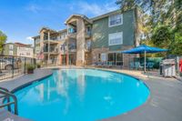 Community pool with lounge and traditional seating. There is also the community leasing office and apartment building in the background.
