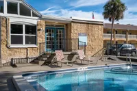 Rectangular community pool with lounge chairs and leasing office in background.