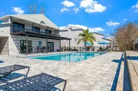 Community pool surrounded with pavers and clubhouse in the background.