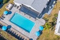 Community pool surrounded with pavers and clubhouse in the background.