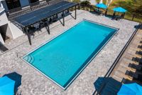 Community pool surrounded with pavers and clubhouse in the background.