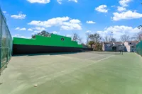 Community tennis court with a bright green wall on the left side.