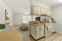 Kitchen with dining table in foreground and living room in background