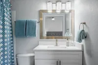 Bathroom with quartz countertop, gold framed mirror and blue towels, hand towels and shower curtain