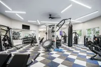 Carpeted fitness center with cardio equipment including treadmills and stationary bicycles overlooking community pool.