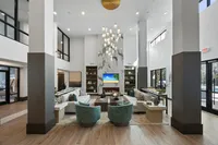 Luxurious high-ceiling lounge with modern decor, plush seating, and stylish chandelier.