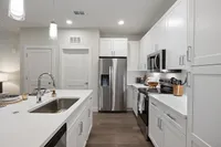 Elegant kitchen with stainless steel appliances, white cabinetry, and warm wood flooring.