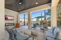 Stylish outdoor lounge area with modern seating, a television, and a cozy fireplace.