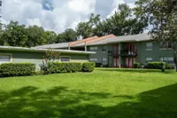 Beautiful apartment complex with lush green lawn, red accents, and a serene outdoor environment.