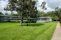 Charming apartment complex with lush green lawns and mature trees under a bright blue sky.