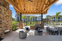 Luxurious outdoor patio with stylish seating areas, wooden pergola, and inviting view of modern apartments surrounded by lush greenery.