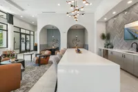 Modern open-concept living space featuring elegant seating, stylish decor, and a chic kitchen area with herringbone backsplash and unique lighting.