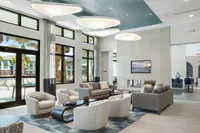 Luxurious modern living room with chic seating area, high ceilings, and expansive windows offering poolside views.
