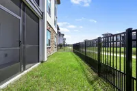 Inviting fenced apartment patio with lush grass and charming stone accents, perfect for relaxation and enjoying sunny days.