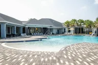 Luxurious outdoor pool area with elegant lounge chairs and shaded seating, surrounded by palm trees and modern architecture, perfect for relaxing and entertainment.