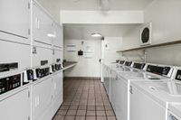 Modern laundry room with stacks of efficient washers and dryers, pristine tile flooring, and ample folding space.