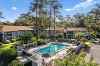Charming apartment complex with a serene outdoor pool area, surrounded by lush greenery and scenic trees.