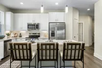 Modern, elegant kitchen with sleek stainless steel appliances, white cabinetry, and a cozy breakfast bar featuring stylish seating.