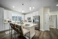 Modern kitchen in a luxury apartment showcasing sleek white cabinets, stainless steel appliances, and an inviting breakfast bar with elegant seating.
