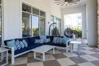 Chic outdoor lounge area with stylish navy and white sofas, modern accent pillows, and inviting hanging chairs, perfect for relaxing.