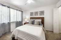 Inviting bedroom with a cozy bed, soft lighting, and elegant decor, framed by natural light from large windows and stylish curtains.