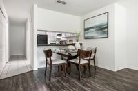 Chic dining area with elegant wooden furniture, hardwood floors, and a modern painting, adjacent to a sleek open kitchen with contemporary appliances.